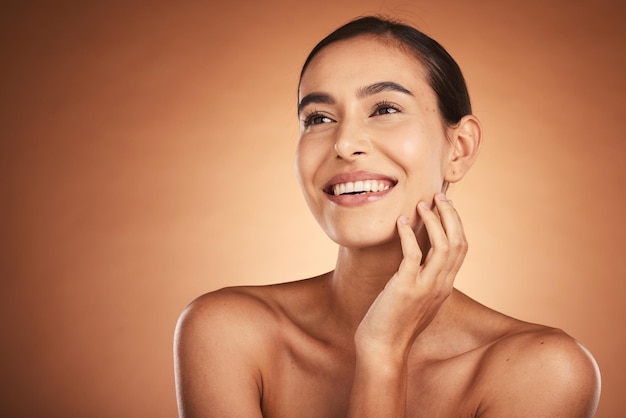 Foto beleza de pensamento e cuidados com a pele da mulher hispânica contra um fundo de estúdio marrom limpe a pele lisa do rosto de uma mulher feliz após o tratamento de cosmetologia e dermatologia para saúde e bem-estar