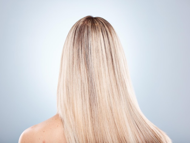 Beleza do cabelo e queratina com uma mulher modelo no estúdio em um fundo cinza para promover um produto para o cabelo Xampu de salão e tratamento com cabelo longo, forte ou saudável na parte de trás de uma cabeça feminina