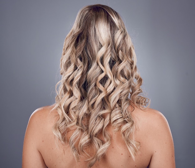 Beleza e estilo de cabelo com uma mulher modelo em estúdio em um fundo cinza para promover tratamento de queratina Penteado encaracolado cuidados com os cabelos e costas com uma mulher posando para cuidados naturais para raízes fortes