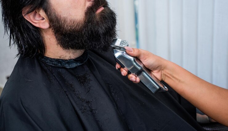 Foto beleza e moda cabelo e barba estilo confiante cara brutal com barbearia mestre profissional barbeador elétrico para hipster barbeiro masculino homem barbudo na cadeira de cabeleireiro no salão