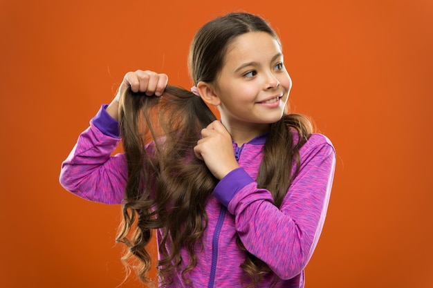 Foto beleza encantadora garota criança ativa com cabelos longos e lindos conceito de cabelo forte e saudável como tratar cabelos cacheados dicas fáceis para fazer penteado para crianças penteado confortável para estilo de vida ativo