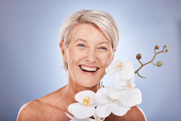 Beleza facial e flores com uma mulher madura no estúdio em um fundo cinza com uma orquídea para cuidados naturais Cosméticos de retrato e planta com uma mulher sênior posando para promover o benefício da natureza