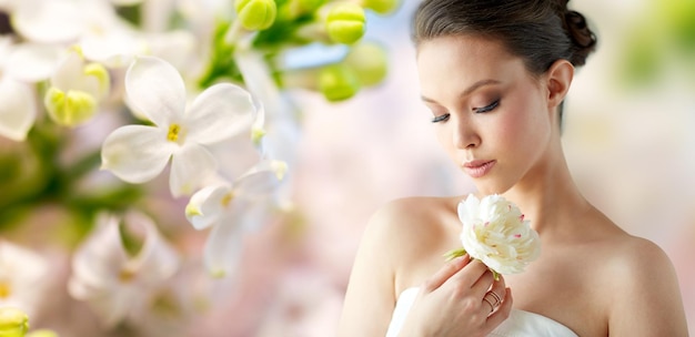 beleza, joias, pessoas e conceito de luxo - linda mulher asiática ou noiva em vestido branco com flor de peônia e anel dourado sobre fundo de flor lilás de primavera natural