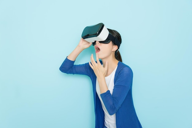 beleza jovem usando óculos de tecnologia de realidade virtual fone de ouvido 3d inovadores procurando site de compras on-line ficando surpreso quando ela vestindo roupas de liberdade em fundo azul.