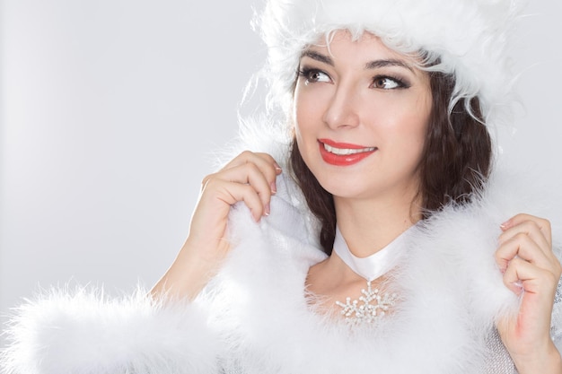 Beleza menina morena com chapéu de Papai Noel em fundo cinza