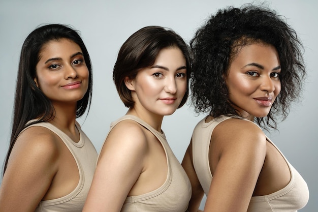Beleza multiétnica e amizade Grupo de belas mulheres de etnia diferente em fundo cinza