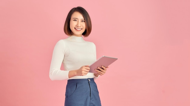 Beleza no trabalho Mulheres jovens confiantes segurando um tablet digital em pé contra um fundo rosa