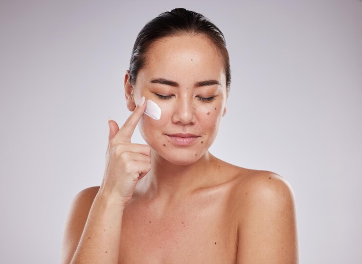 Foto beleza para a pele e creme facial para mulheres em estúdio para cuidados de bem-estar e cosméticos em fundo cinza modelo facial e garota asiática relaxam com pele de protetor solar de luxo e tratamento com produto
