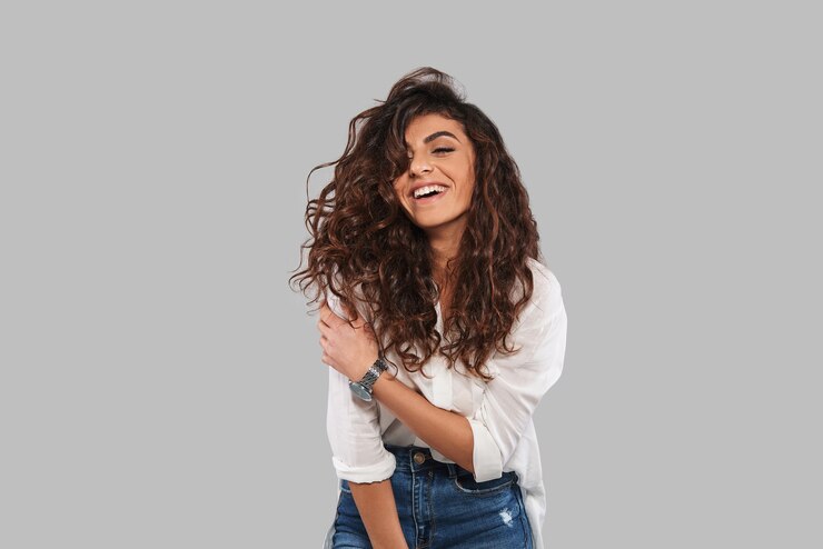 Beleza Pura. Mulher jovem e atraente sorrindo em pé contra um fundo cinza
