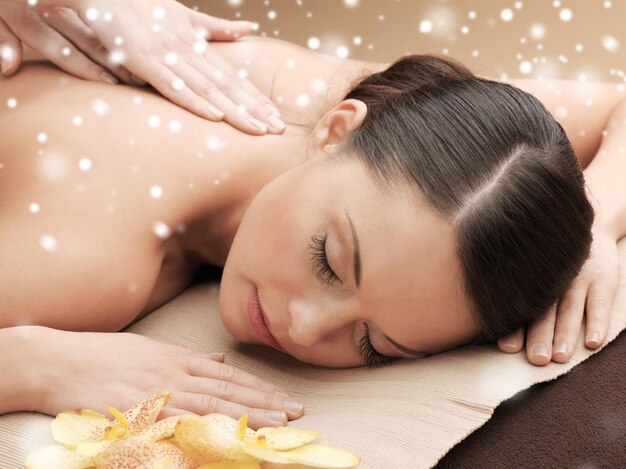 beleza, saúde, férias, pessoas e conceito de spa - bela jovem no salão de spa recebendo massagem