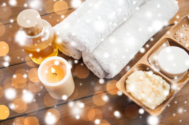 beleza, spa, cuidados com o corpo, cosméticos naturais e conceito de bem-estar - sabonete com velas e toalhas de banho na mesa de madeira sobre luzes e neve