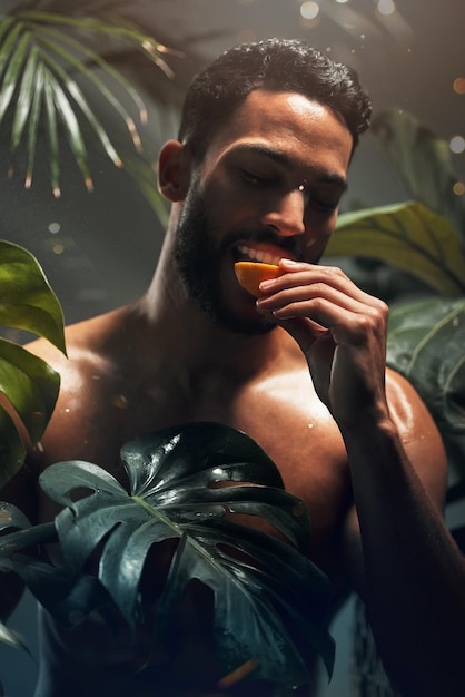 Beleza tropical e modelo comendo frutas na selva para dieta saudável e nutrição de bem-estar no paraíso Palmeiras exóticas e cuidados com a pele hidratada do homem com desintoxicação alimentar saudável e natural