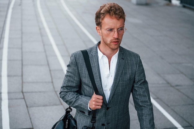 Beleza urbana Jovem empresário com roupa formal cinza está ao ar livre na cidade