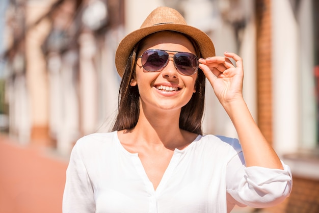 Beleza urbana. Mulher jovem e bonita ajustando o chapéu e sorrindo ao ar livre