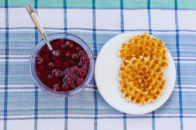 Belgische Kartoffelwaffeln mit Prosciutto-Kirschtomaten-Basilikumblättern und heißer Tomatenmarmelade oder würziger Sauce Serviert Frühstücksbrunch auf hellem Hintergrund