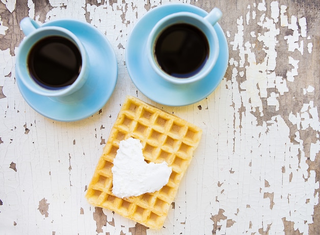 Belgische Waffel und zwei Tasse Kaffees auf einem alten Holztisch