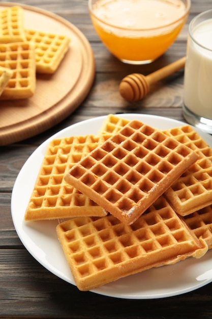 Belgische Waffeln. Belgische Waffeln mit Honig und Milch. Frisch gebackene belgische Waffeln. Vertikales Foto