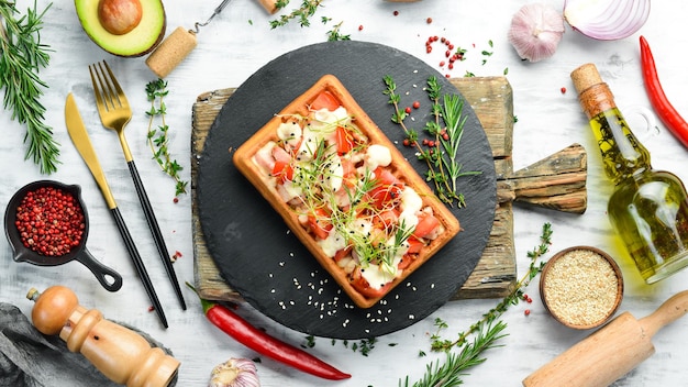 Belgische Waffeln mit Bacon-Tomaten und Microgreens Frühstück auf einer schwarzen Steinplatte