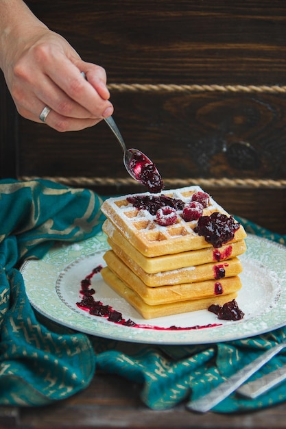 Belgische Waffeln mit Beeren werden mit Marmelade gegossen