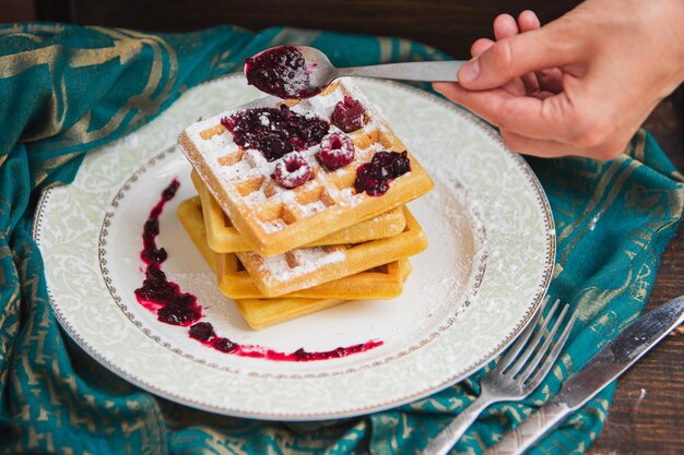 Belgische Waffeln mit Beeren werden mit Marmelade gegossen