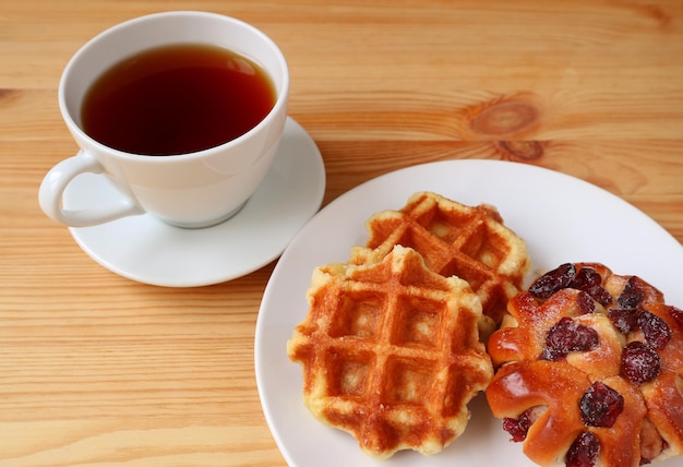 Belgische Waffeln mit einer Tasse heißen Tee auf einem Holztisch