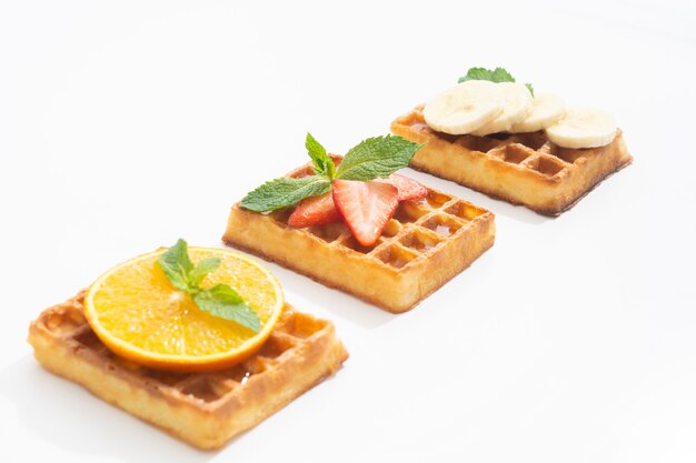 Belgische Waffeln mit Erdbeerbanane und Orange mit Sirup auf Weiß