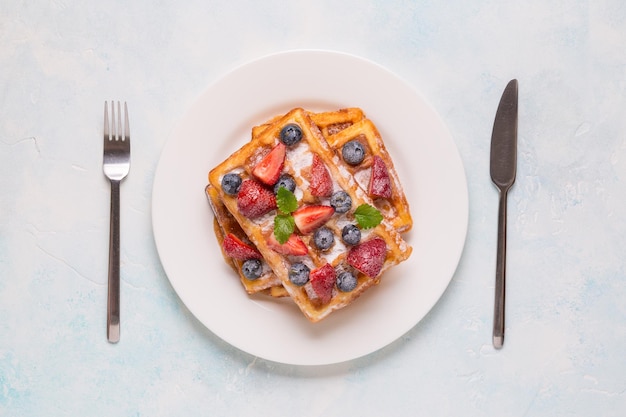 Belgische Waffeln mit Erdbeeren, Blaubeeren und Sirup, hausgemachtes, gesundes Frühstück, Draufsicht