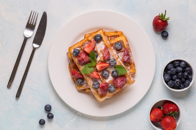 Belgische Waffeln mit Erdbeeren, Heidelbeeren und Sirup, hausgemachtes, gesundes Frühstück