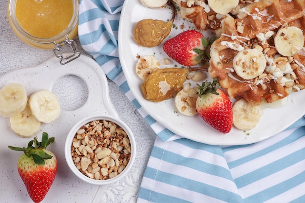 Belgische Waffeln mit Sirup, Beeren und Honig, Frühstück auf hellem Hintergrund, selektiver Fokus