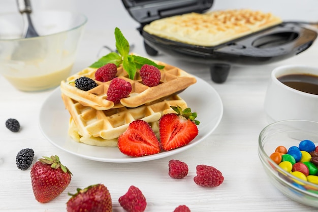 Belgische Waffeln mit verschiedenen Beeren auf weißem Teller. Süße Waffeln auf einem weißen Teller