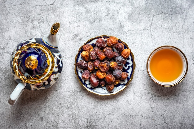 Beliebtes Essen während der Iftar-Trockendattel-Teekanne mit schwarzem Tee auf Betonhintergrund Draufsicht Flache...