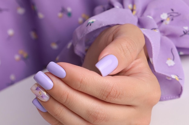 Belíssima mão feminina com unhas de manicure roxo desenho de flores