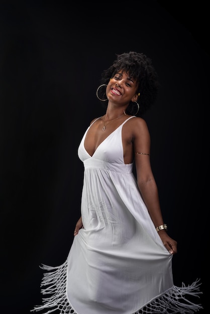 Bella belleza con cabello de poder negro de pie moviendo su vestido blanco
