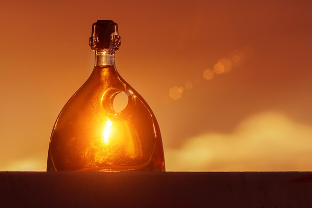 Bella botella decorativa con un agujero redondo al atardecer