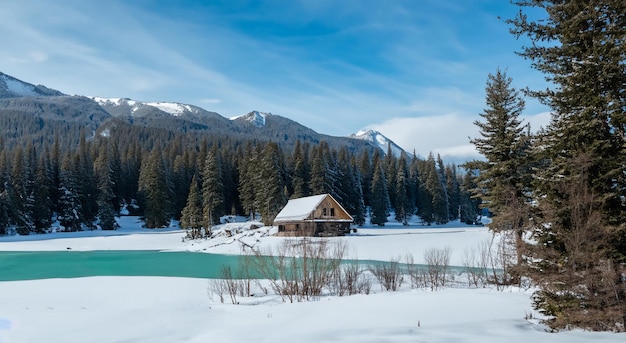 Bella cabaña en el medio de una montaña llena de nieve con un gran lago