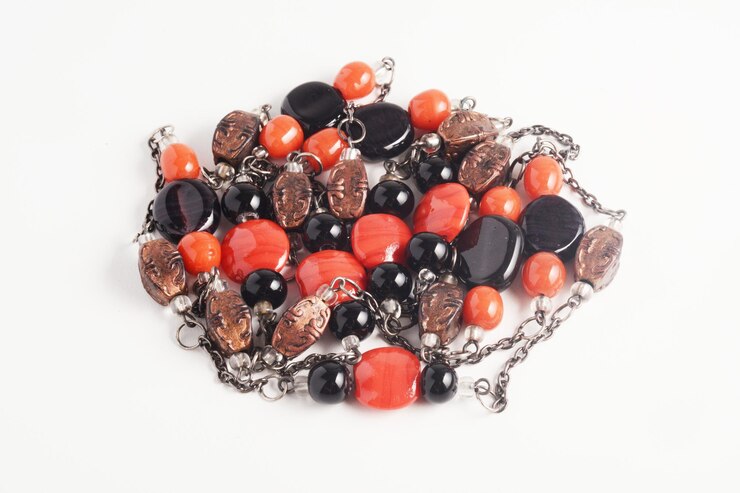 Bella cadena y collar de cuentas hechas de cuentas de cobre negras y naranjas sobre fondo blanco