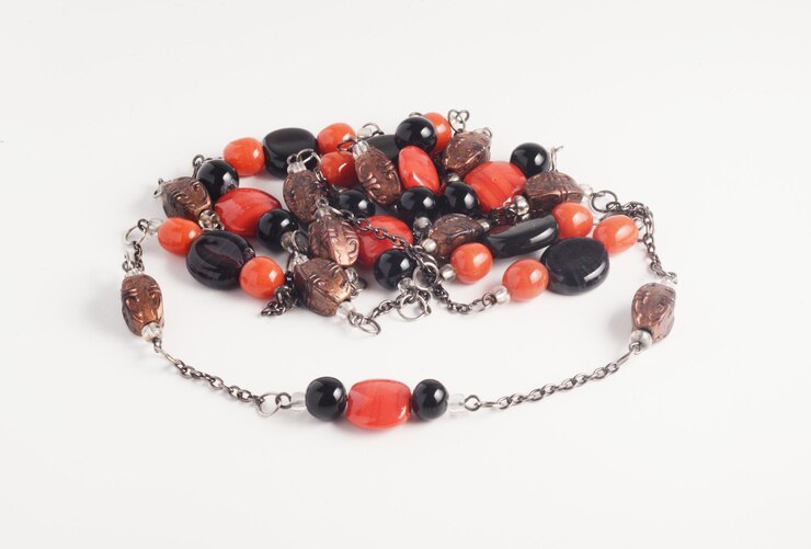 Bella cadena y collar de cuentas hechas de cuentas de cobre negras y naranjas sobre fondo blanco