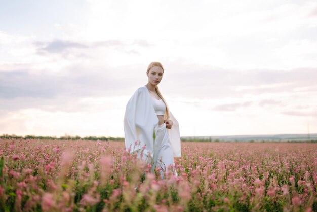 Bella chica romántica al aire libre al atardecer Mujer joven con ropa elegante posando en el campo en flor