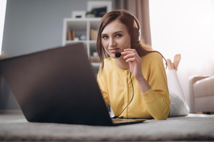 Bella dama en auriculares tirados en el suelo con portátil abierto