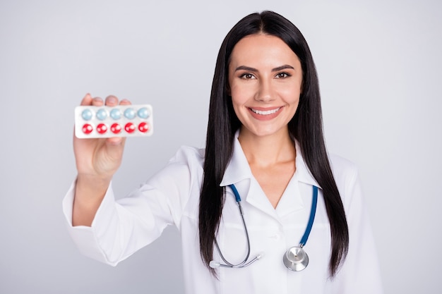 Bella dama doc profesional proponiendo pastillas sobre fondo gris