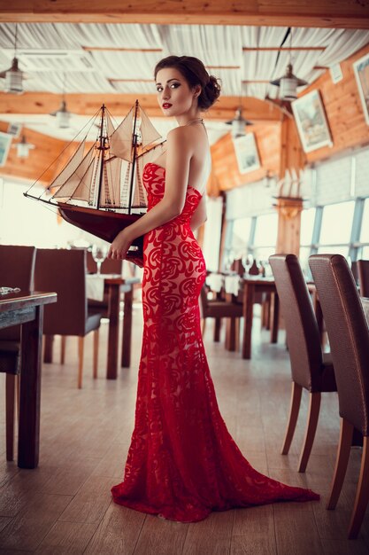 Foto bella dama en vestido rojo en el restaurante.