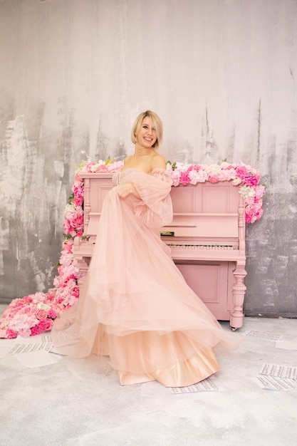 Bella dama en vestido rosa y piano rosa. Foto de alta calidad