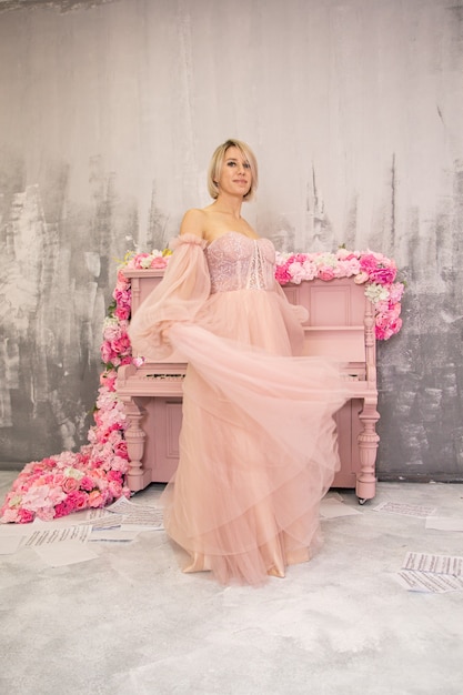 Bella dama en vestido rosa y piano rosa