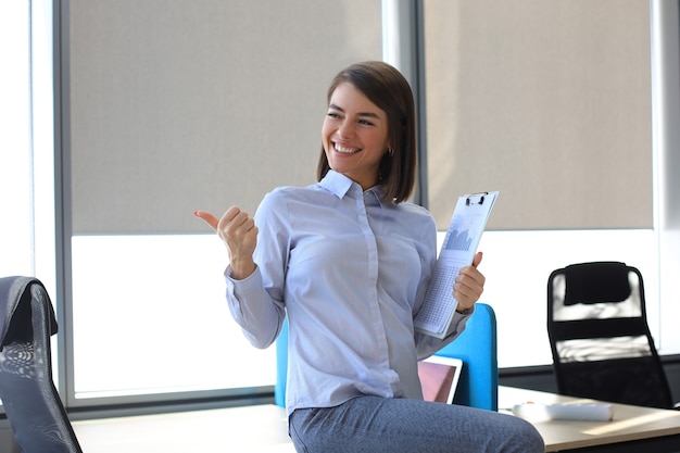 Foto bella empresaria está expresando alegría en la oficina mientras recibe buenas noticias.