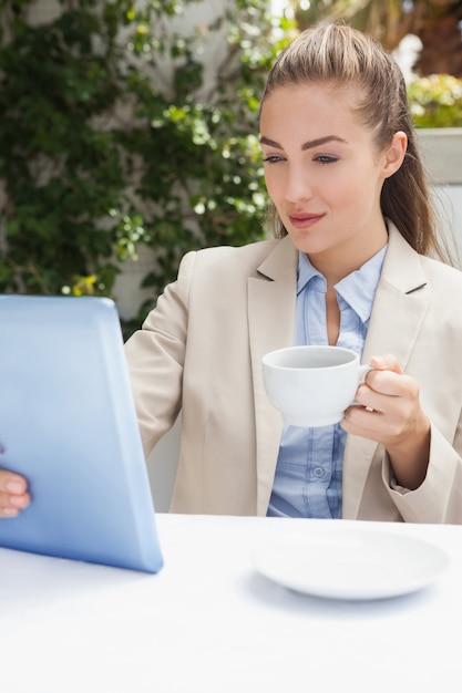 Bella empresaria tomando un café con tableta