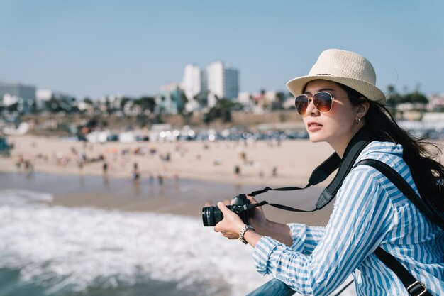 una bella fotógrafa relajándose y parada cerca de la playa