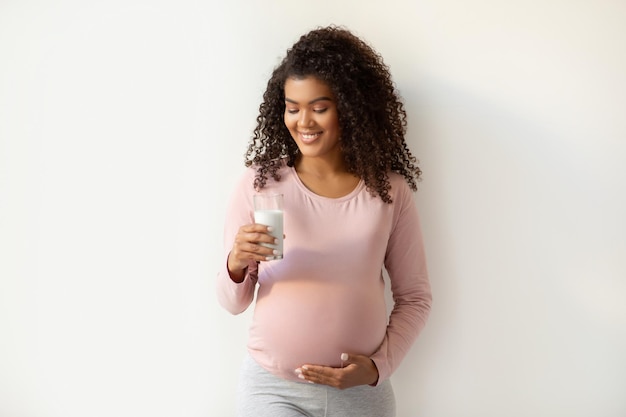 Bella futura madre afroamericana con un vaso de leche y una sonrisa