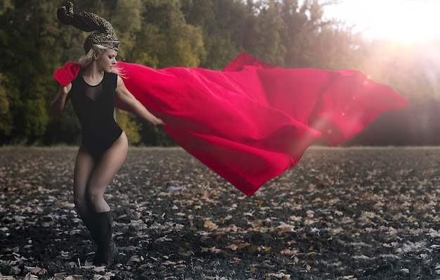 Foto bella guerrera rubia con casco dorado y capa roja en el viento