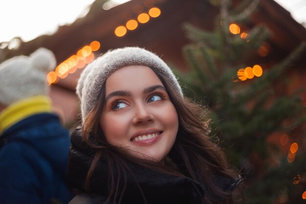 Foto bella joven de cabello oscuro feliz en un mercado europeo de navidad vacaciones año nuevo