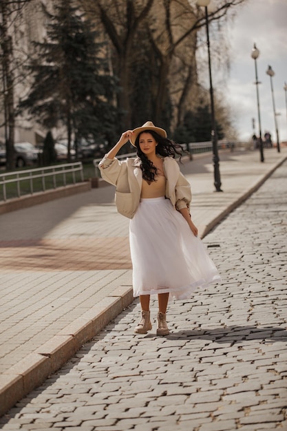 bella joven caminando por la ciudad con falda blanca y sombrero